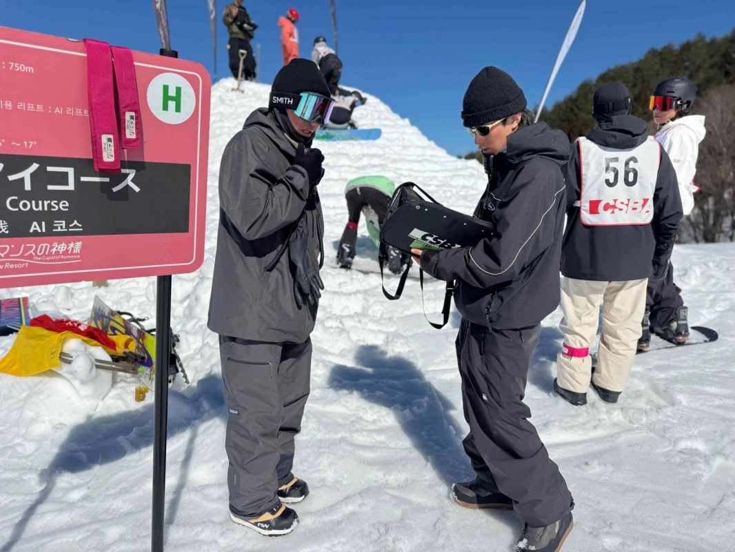 スキー場でコース案内板の近くに立つ人物たち、大会運営の様子