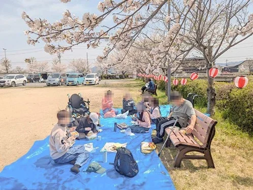 桜が満開の公園でピクニックを楽しむ人々