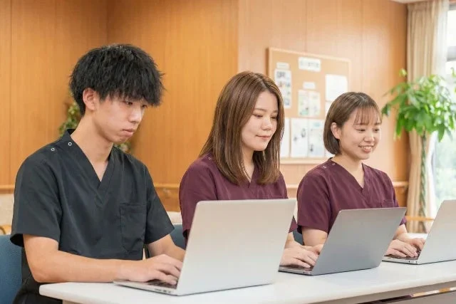 スクラブを着た男女3人がノートPCで作業している様子