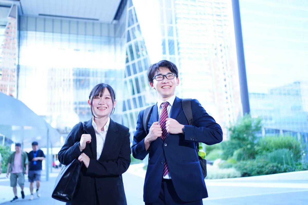 都会のビル群を背景に笑顔の若いビジネスパーソン