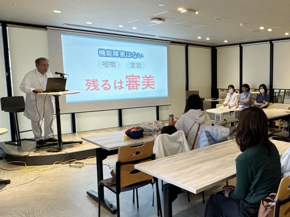 白衣の講師がプレゼンテーションを行う様子