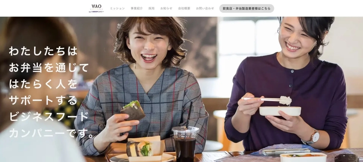 明るい雰囲気の中で、二人の女性が笑顔でランチを楽しんでいます。