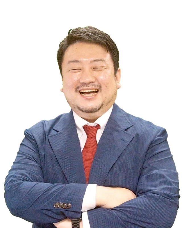 紺色のスーツと赤いネクタイを着用したアジア人男性が、目を閉じて満面の笑みを浮かべ、腕を組んでいるポートレート写真