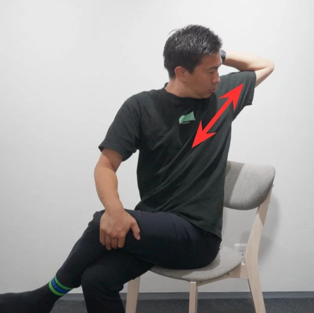 男性が椅子に座って胸から肩にかけてストレッチをしている画像