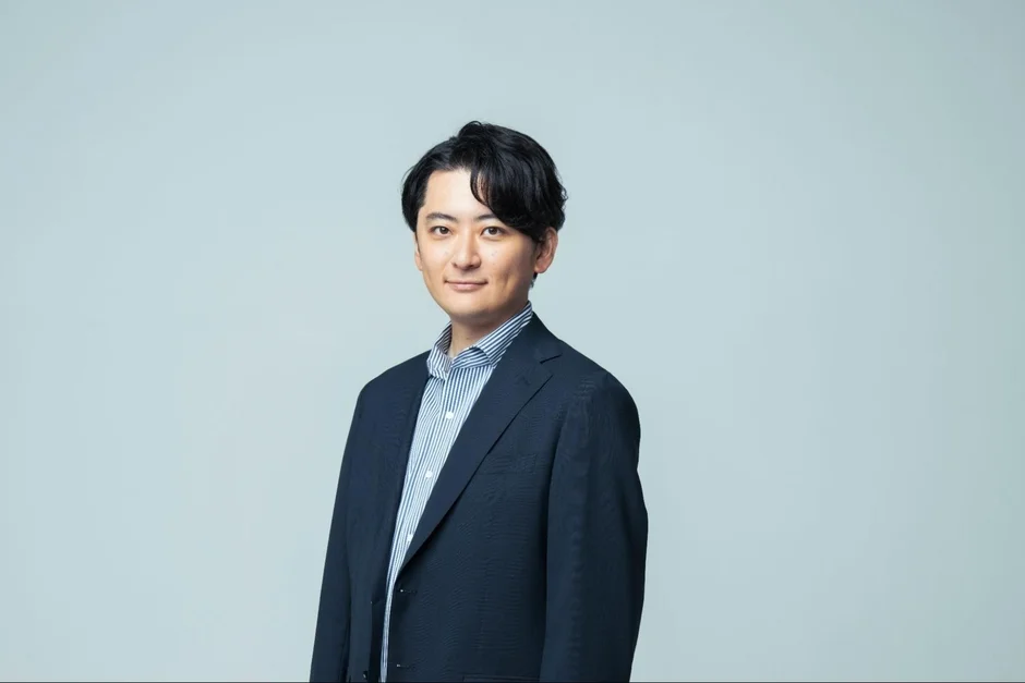 ネイビーのスーツとストライプ柄のシャツを着用した日本人男性