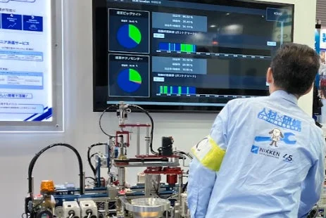 稼働データを示すディスプレイを観察する人物