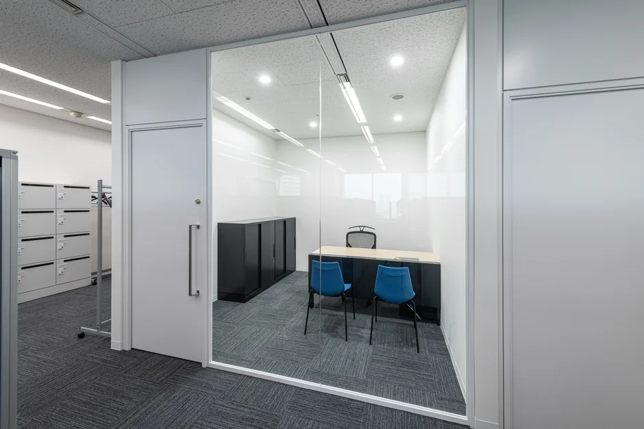 ガラス張りのパーテーションで仕切られたモダンなオフィス空間