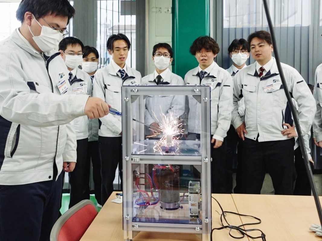 火花が散る実験を見学する若者たち