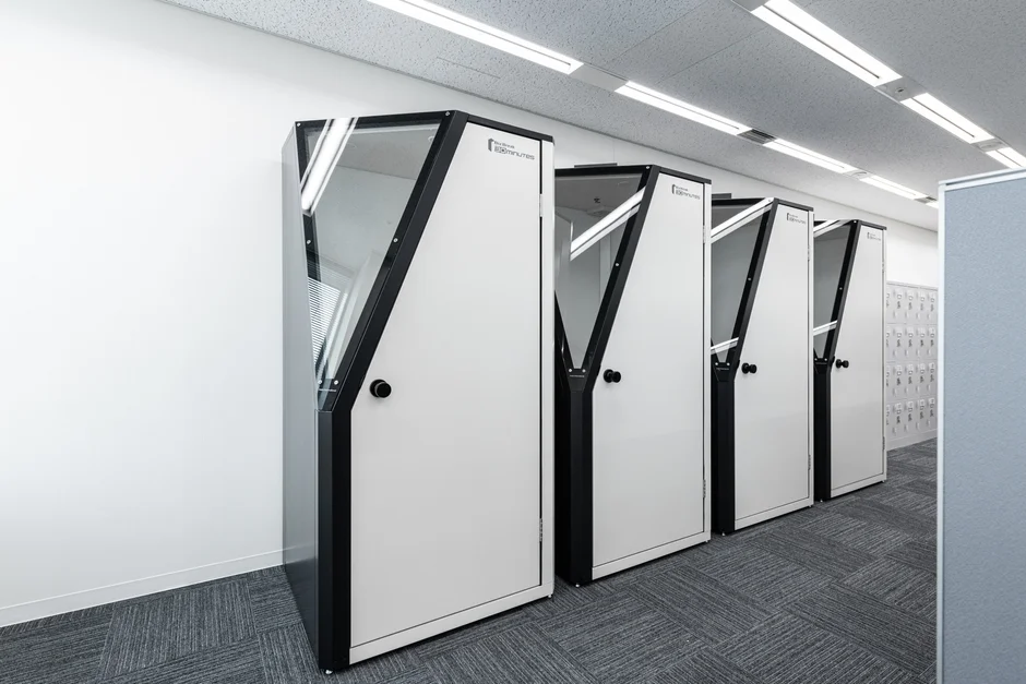 オフィスの一角に設置された、白い扉と黒いフレームが特徴的なモダンな個室ブース