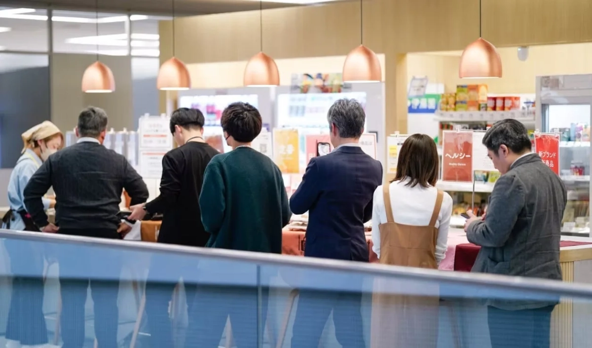 店内のカウンターに集まった人々が、商品やディスプレイを見ている様子。