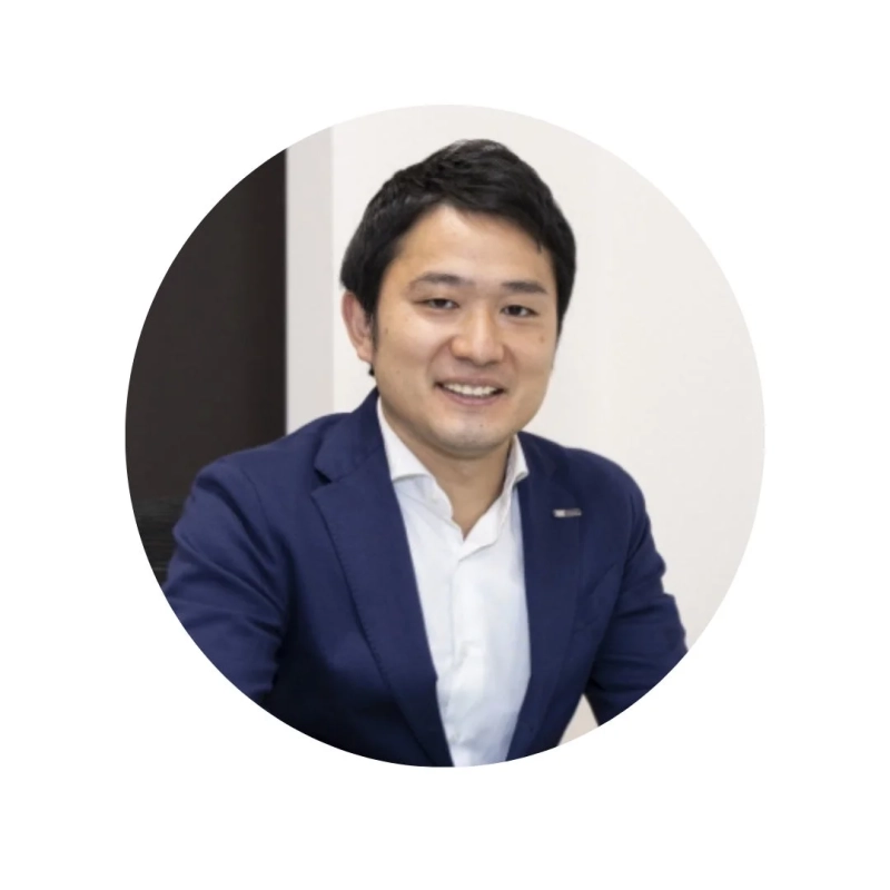 青いスーツと白いシャツを着用し、笑顔でカメラを見つめるアジア人男性のプロフィール写真