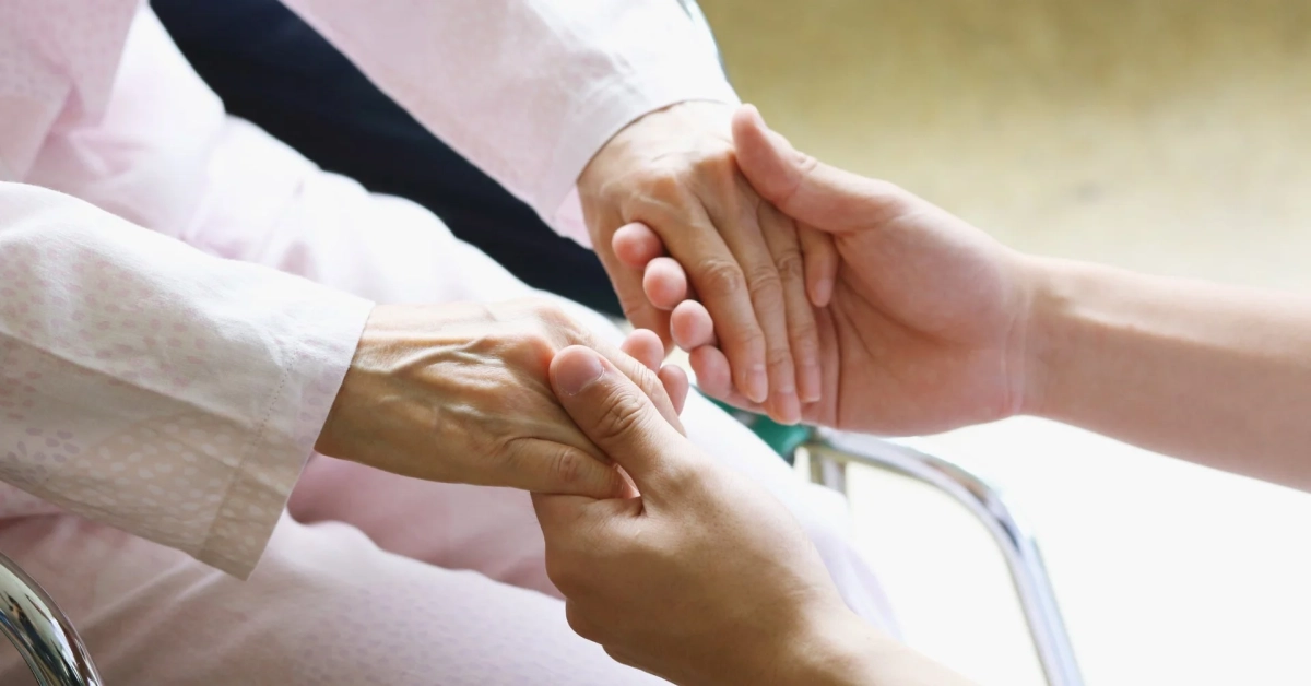 高齢者の手と若者の手が優しく握り合わされている様子