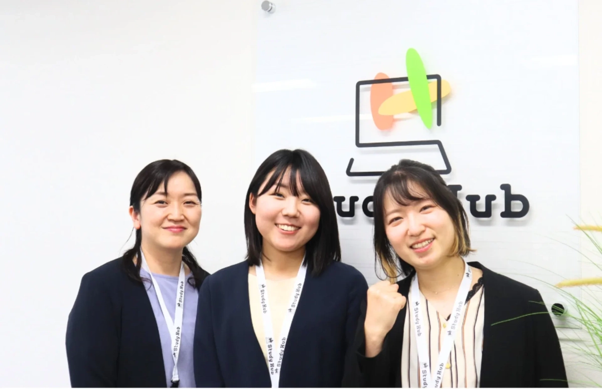 Study Hubのロゴの前で、3人の女性スタッフが笑顔でポーズをとっています。全員がStudy Hubのストラップを着用しており、和やかな雰囲気が伝わります。