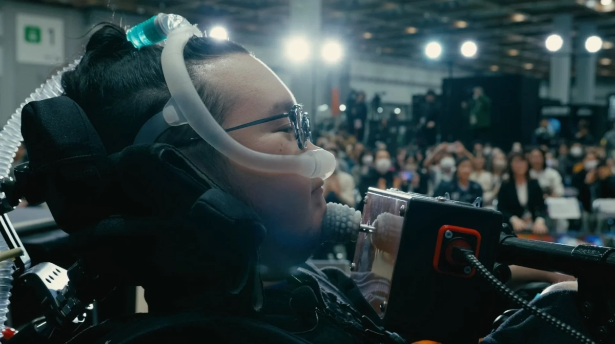 呼吸器と支援技術を装着した人物