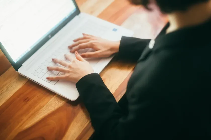 ノートパソコンをタイピングする手元