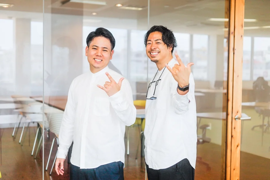笑顔でロックサインをする二人の男性