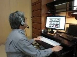 ヘッドセットを装着した男性が、パソコンのモニターに向かってデスクワークをしている様子