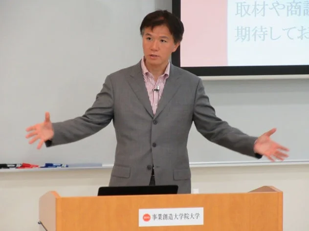 スーツを着た男性が教壇でプレゼンテーションを行っている