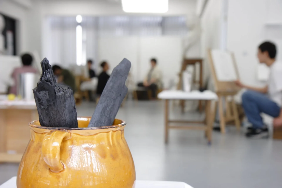 木炭が立てられた壺と制作に励む人々