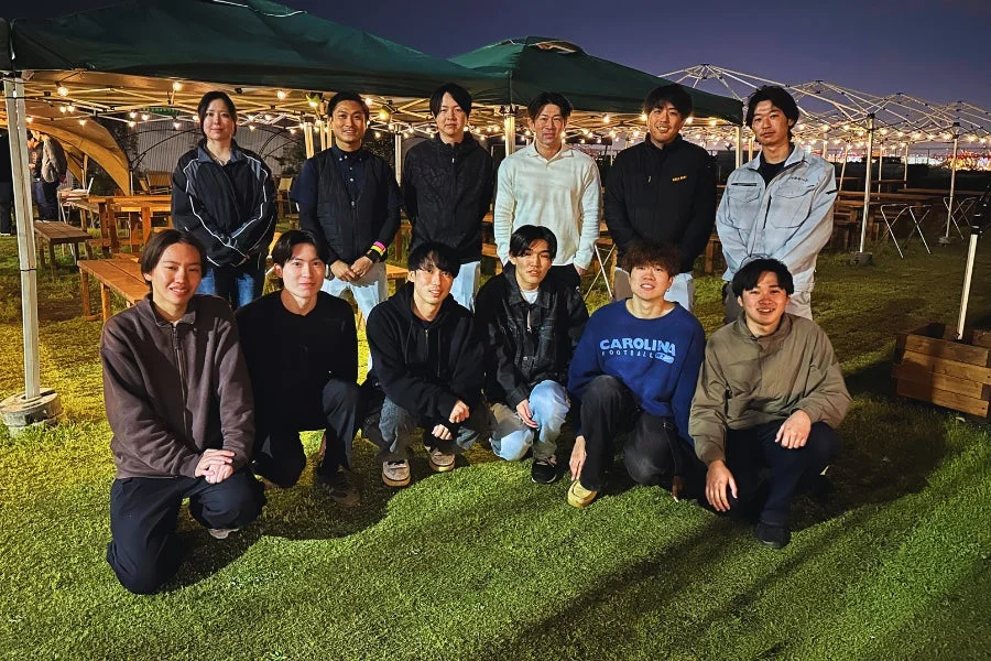 夜の屋外イベントで集合写真を撮るグループ