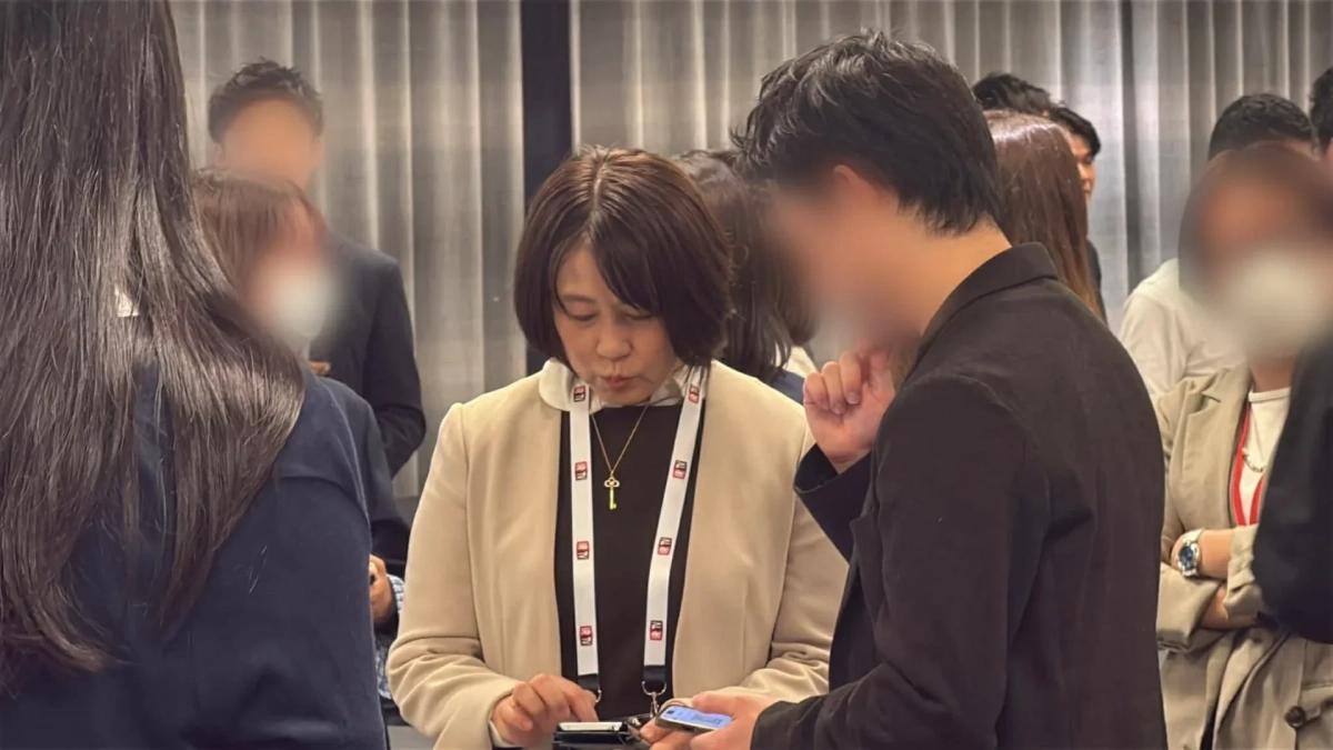 屋内のイベント会場で、ランヤードを着用した人々が交流しています。