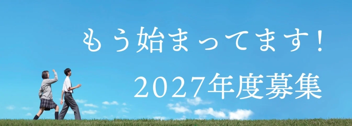 青い空と緑の丘を背景に、制服姿の男女学生が歩いている画像