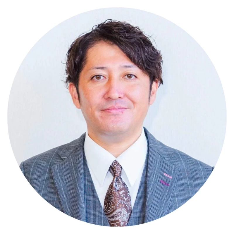グレーのチェック柄のスーツとベストを着用し、茶色のペイズリー柄のネクタイを締めたアジア人男性のプロフィール写真