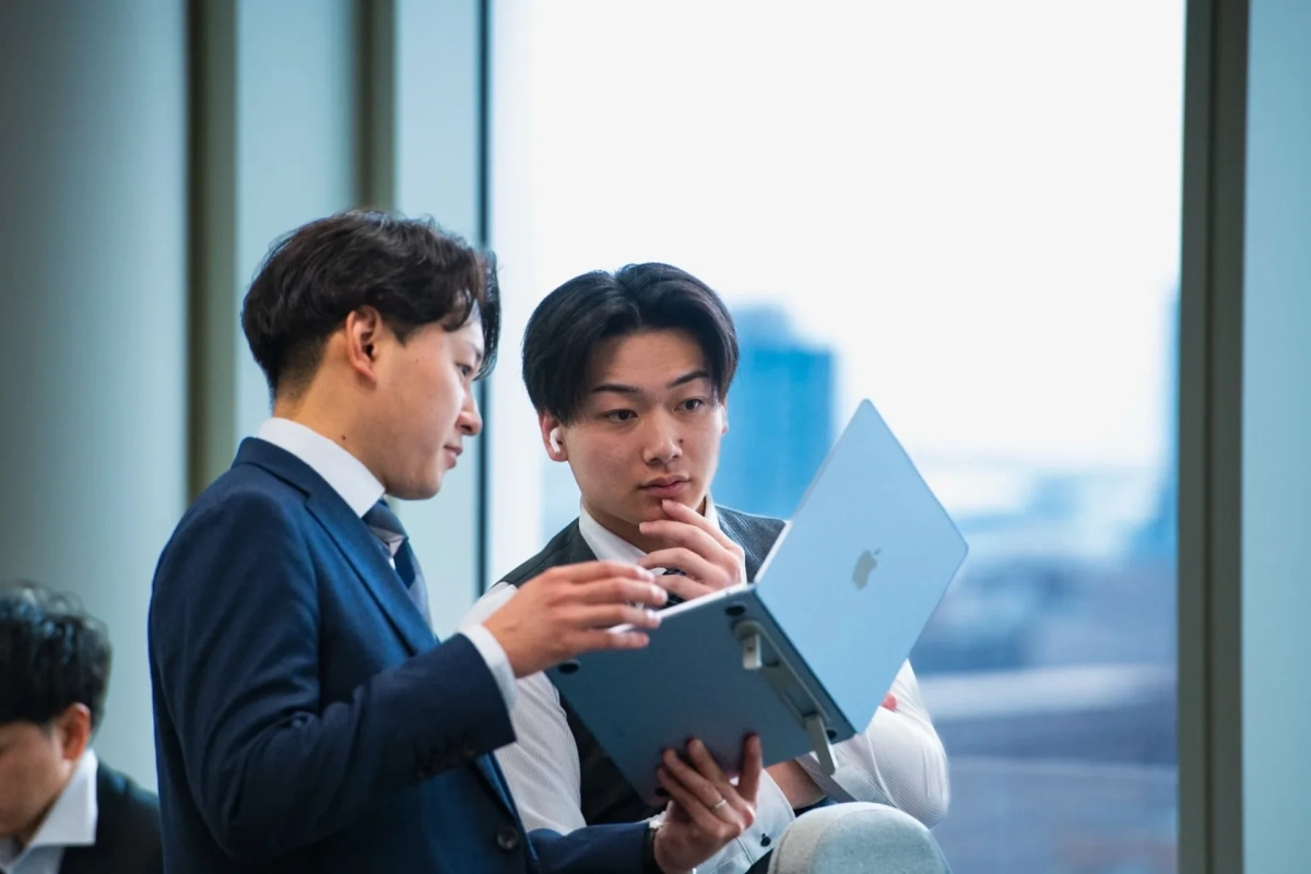 ノートパソコンを囲んで話し合う若手社員