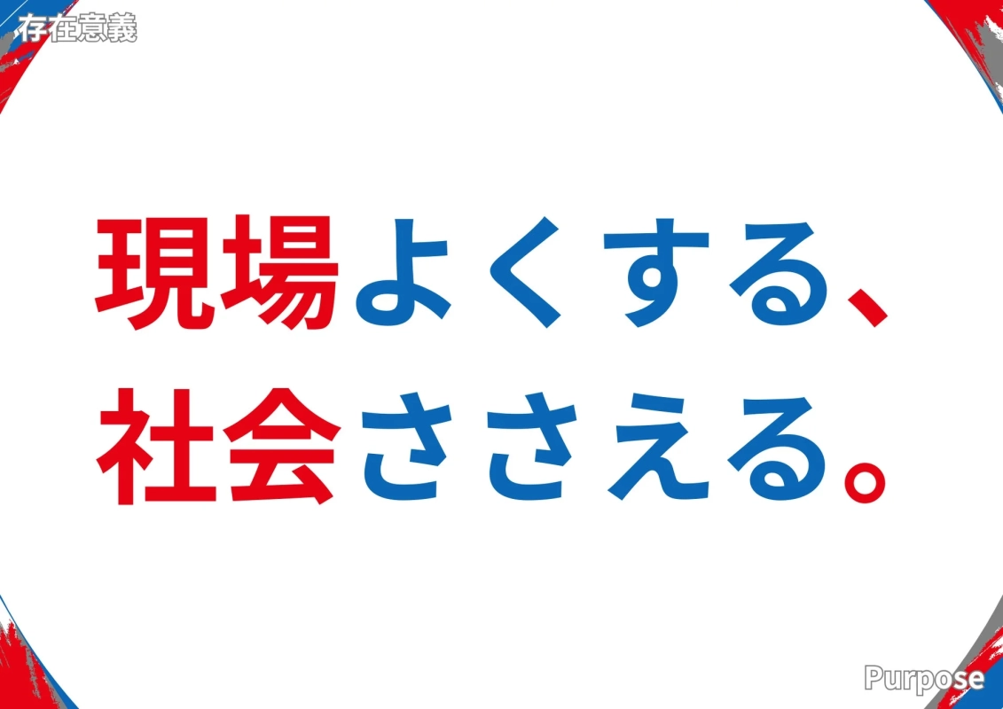 白地に赤と青の文字で「現場よくする、社会ささえる。」というスローガンが書かれた画像です。左上には「存在意義」、右下には「Purpose」の文字も確認でき、企業理念や目標を示すメッセージ性の強いデザインとなっています。