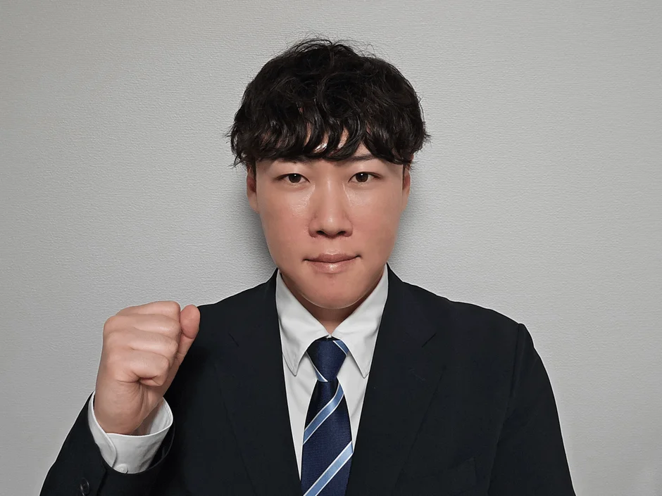 スーツを着たアジア人男性がカメラに向かって拳を握り、決意や応援のポーズ