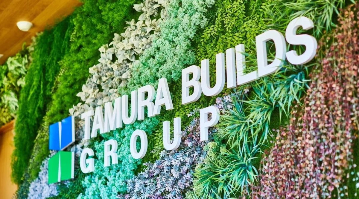 TAMURA BUILDS GROUPのロゴが飾られた緑の壁