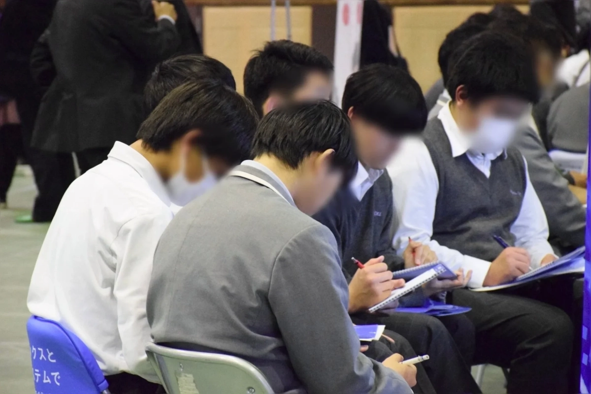 複数の若者が集団で座り、ノートに何かを書き込んでいる様子