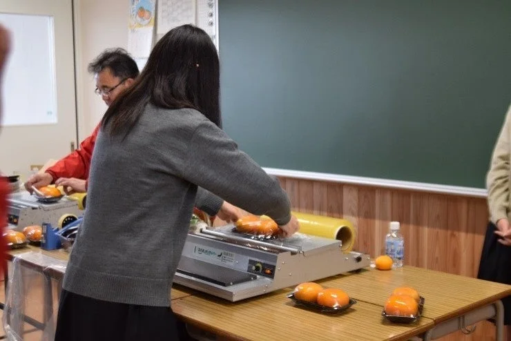 果物などのパック詰めを体験する学生