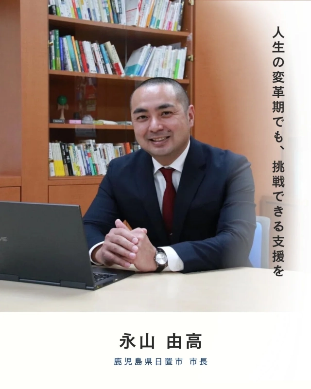 スーツ姿の永山由高日置市長が、オフィスで笑顔を見せている写真