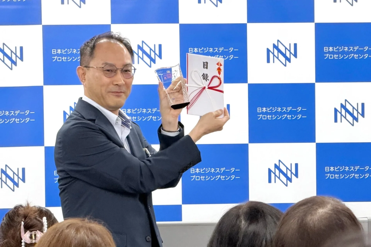トロフィーと目録を持つ受賞者
