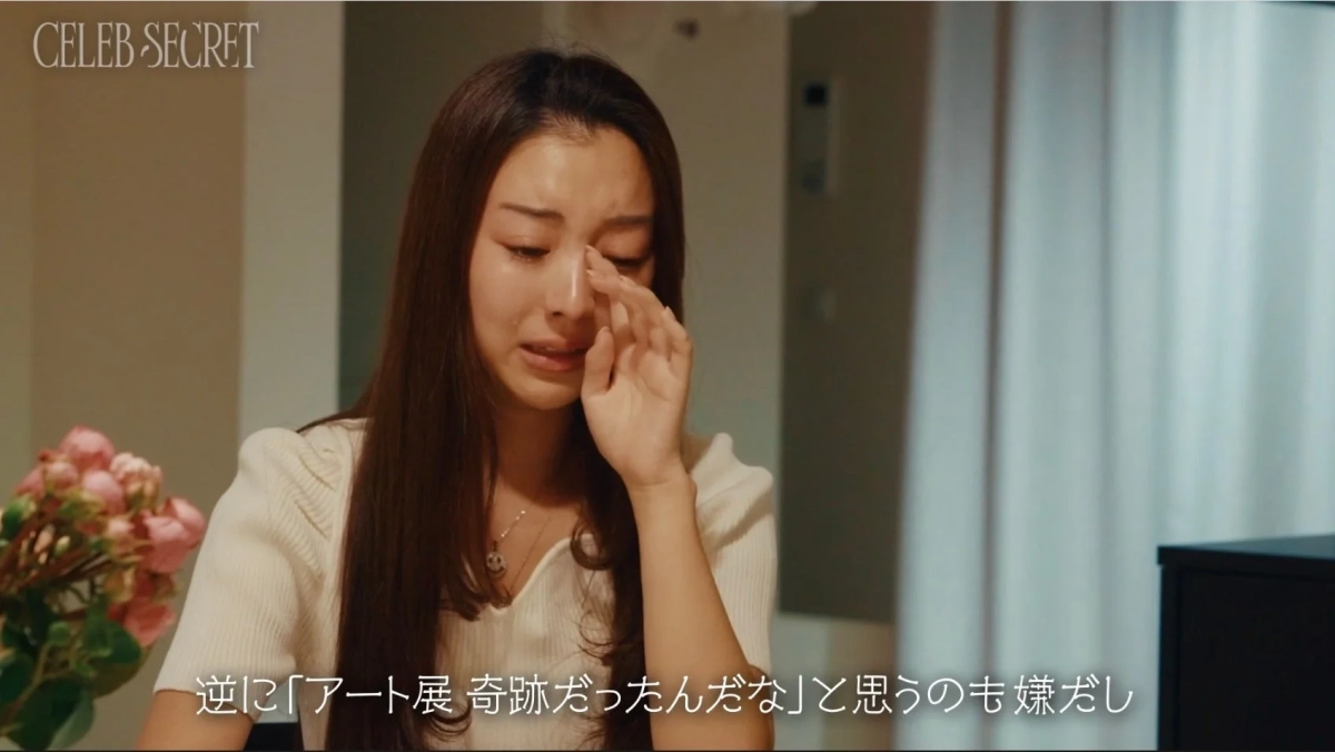 長い髪の女性が悲しそうに涙を拭っている様子