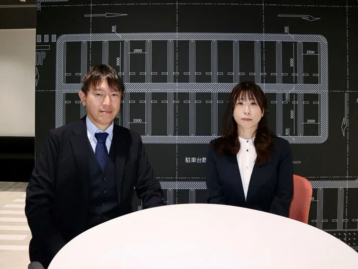 ビジネススーツを着た男女2人が白いテーブルに座る