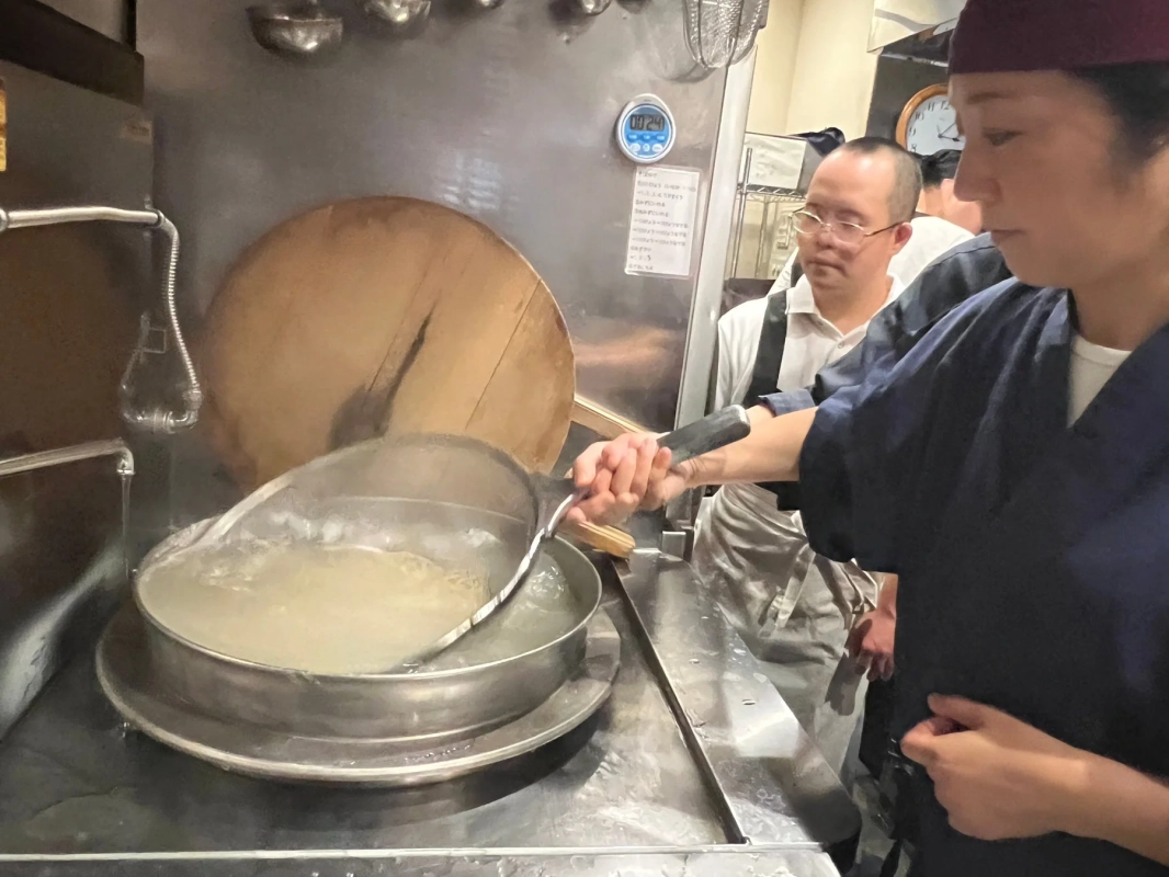 厨房で調理師が麺を茹でている様子