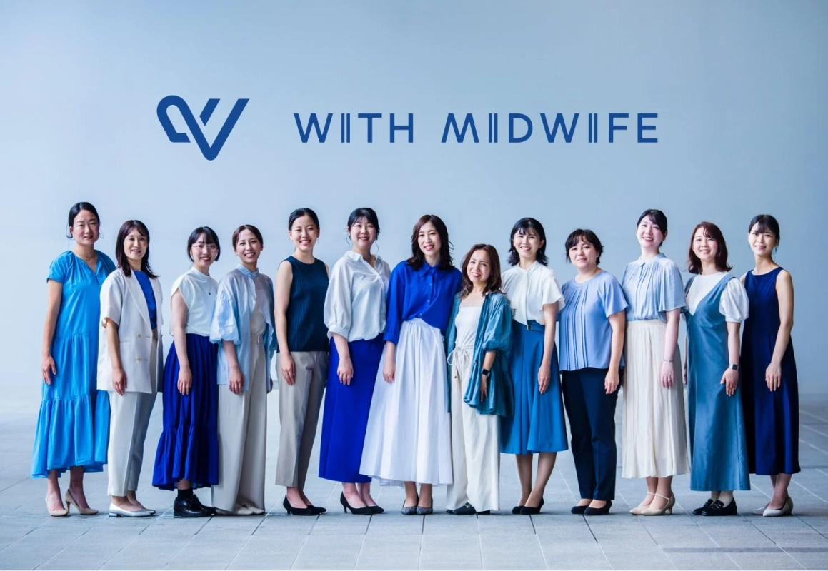 「WITH MIDWIFE」のロゴと文字を背景に、青や白の衣装をまとった日本人女性のグループが笑顔で並ぶ集合写真