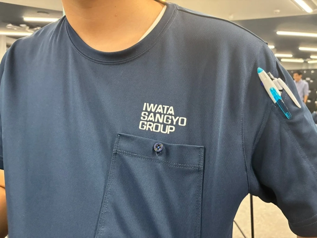 IWATA SANGYO GROUPのロゴが入った紺色のTシャツの胸元
