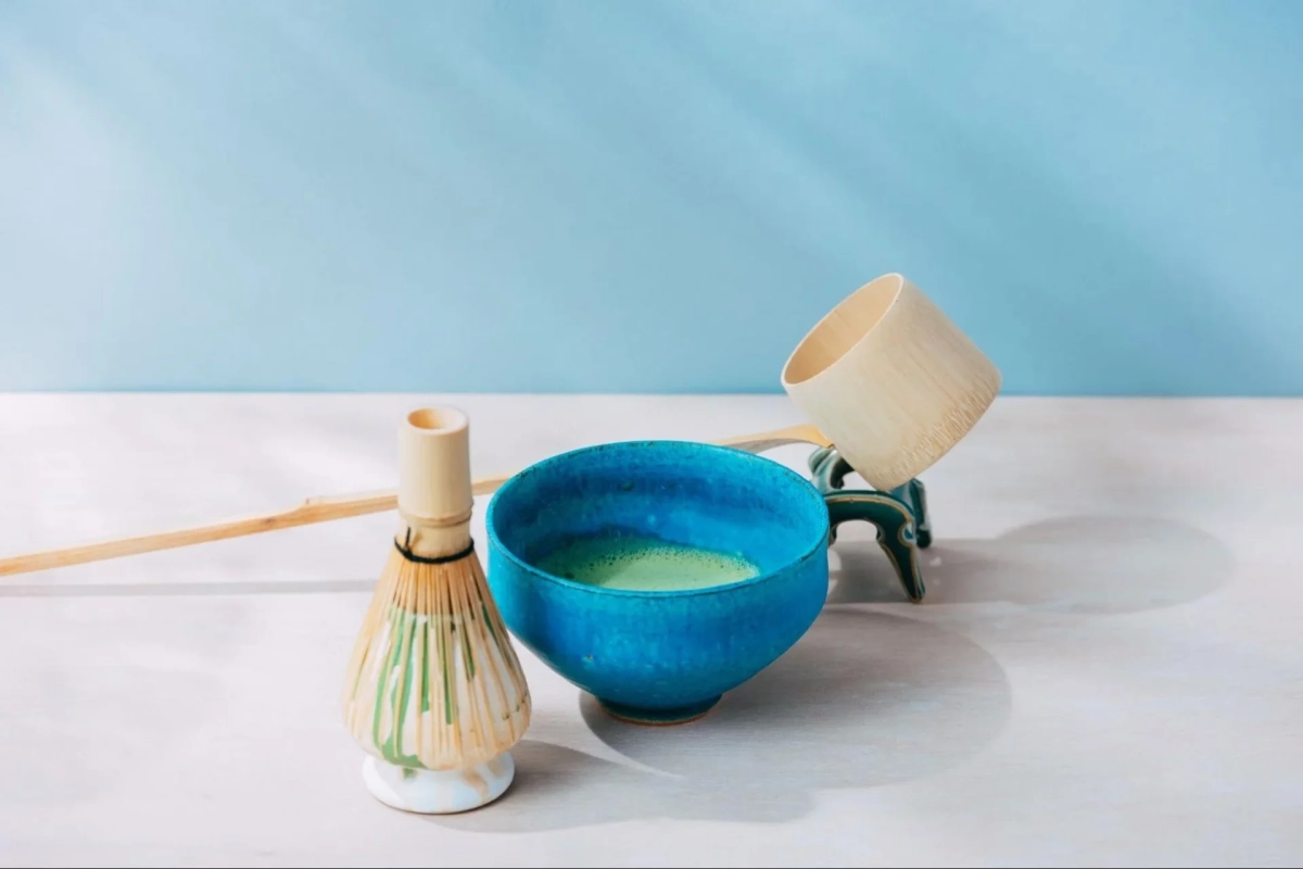 鮮やかな青い茶碗に泡立てられた抹茶と、茶筅、茶杓が並ぶ、静かで美しい和の情景