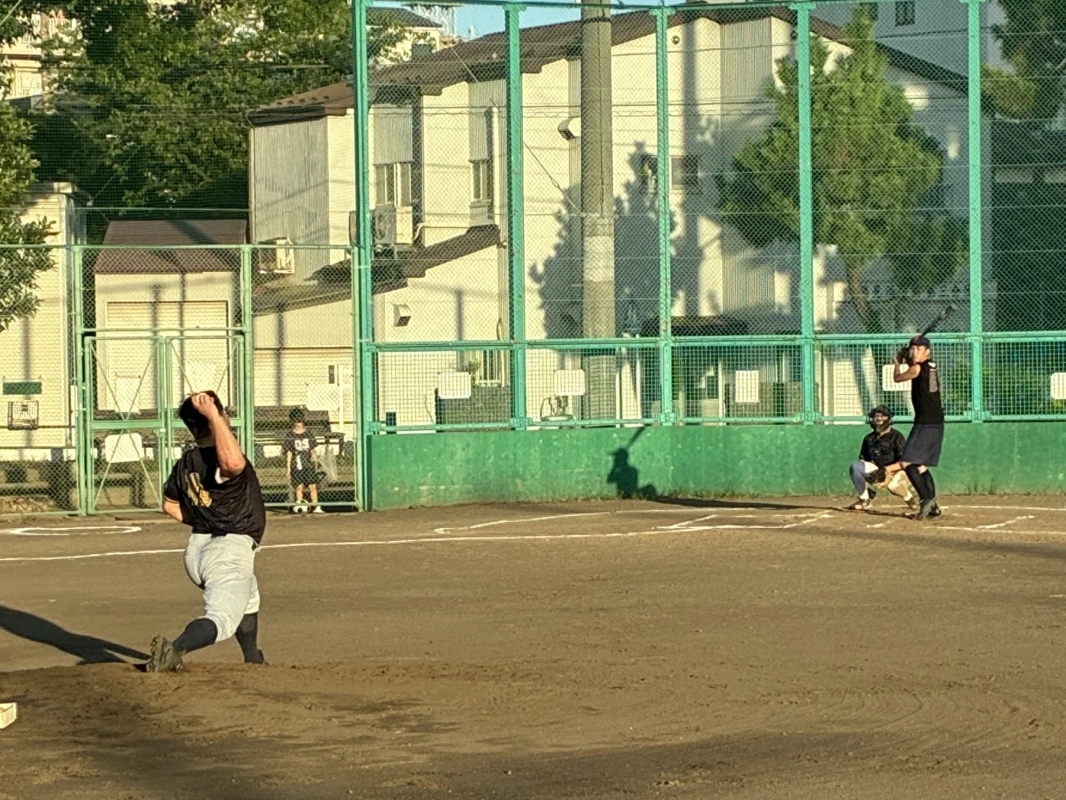 晴れた日の野球場で、ピッチャーが投球動作に入り、バッターがバットを構えている瞬間